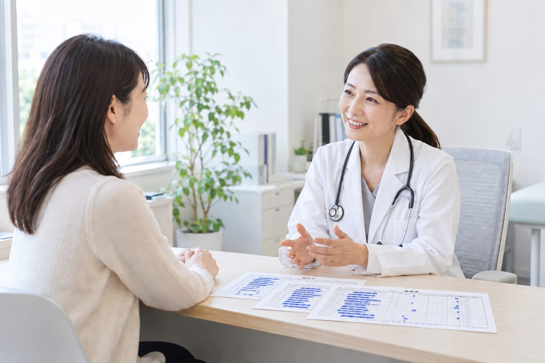 印刷した睡眠表を机に置き、明るい診察室で医師と穏やかに話す患者